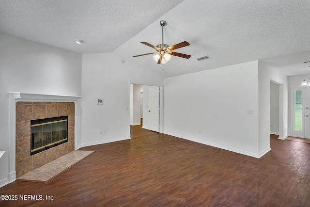 unfurnished living room featuring dark wood-style flooring, visible vents, ceiling fan, and a tiled fireplace