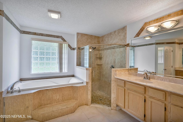 full bath featuring a textured ceiling, tile patterned flooring, a garden tub, vanity, and a stall shower