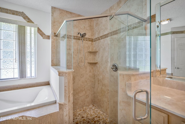 full bath featuring a stall shower, a garden tub, and a textured ceiling