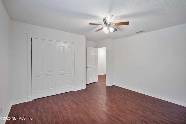 unfurnished bedroom featuring dark wood finished floors, a closet, visible vents, a textured ceiling, and baseboards