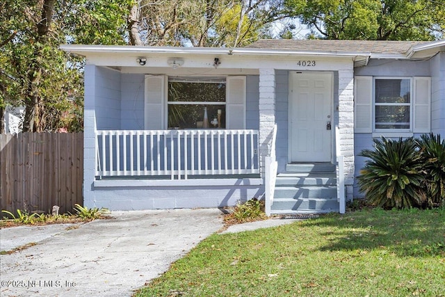 view of front of home featuring a front yard, covered porch, and fence