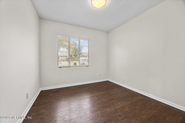 empty room featuring baseboards and dark wood finished floors