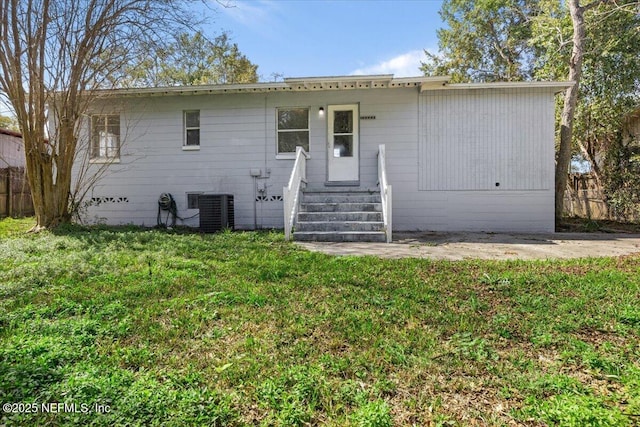 ranch-style house with entry steps, fence, central AC unit, and a front lawn