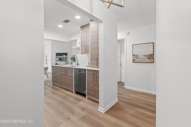 kitchen featuring light wood-style flooring, visible vents, light countertops, and stainless steel dishwasher