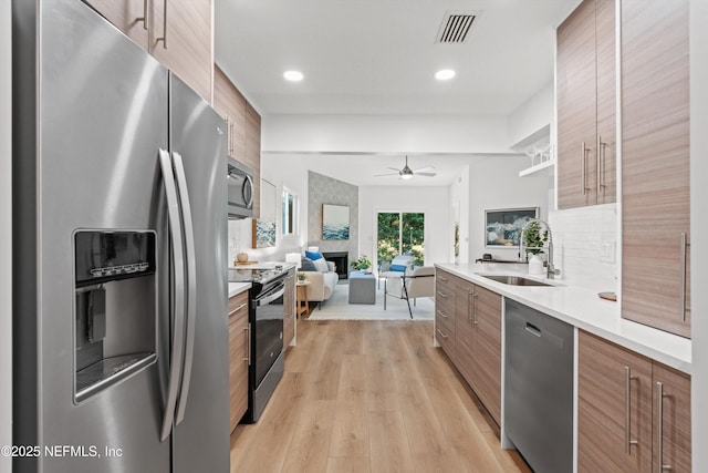 kitchen with brown cabinets, visible vents, appliances with stainless steel finishes, a sink, and modern cabinets