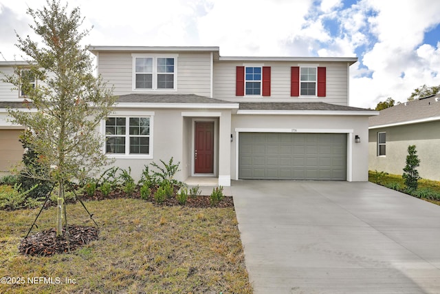 traditional-style house with driveway, a shingled roof, an attached garage, and stucco siding