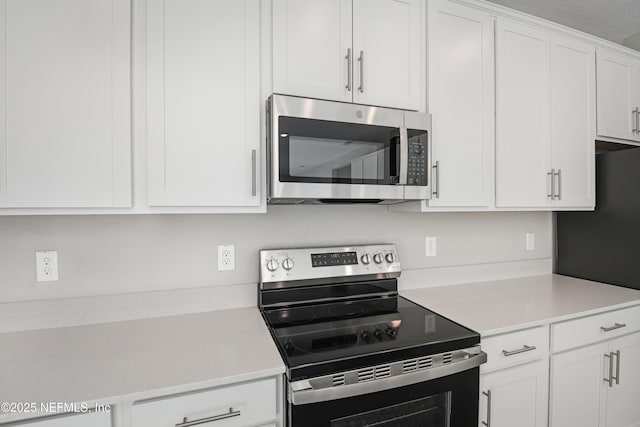 kitchen featuring stainless steel appliances, light countertops, and white cabinetry