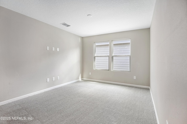 carpeted empty room with a textured ceiling, visible vents, and baseboards