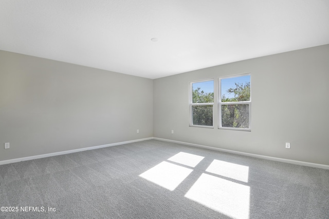 empty room featuring baseboards and light colored carpet