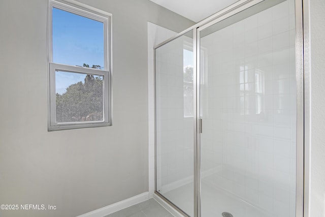 bathroom with a stall shower, plenty of natural light, and baseboards