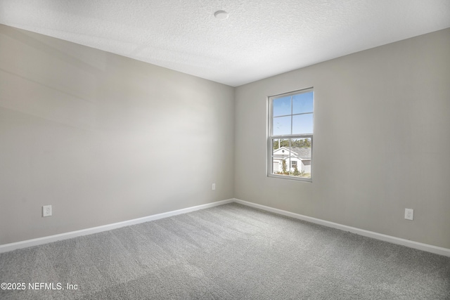 carpeted spare room with a textured ceiling and baseboards