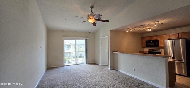 kitchen featuring baseboards, brown cabinetry, light colored carpet, appliances with stainless steel finishes, and a textured ceiling