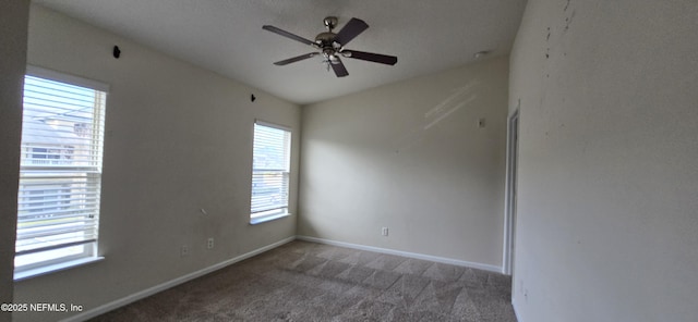 carpeted spare room with ceiling fan and baseboards