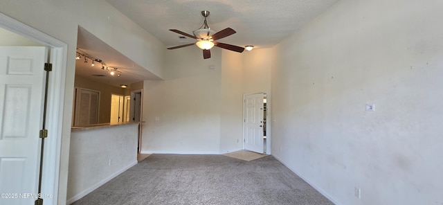 spare room featuring light carpet, a towering ceiling, a ceiling fan, and baseboards