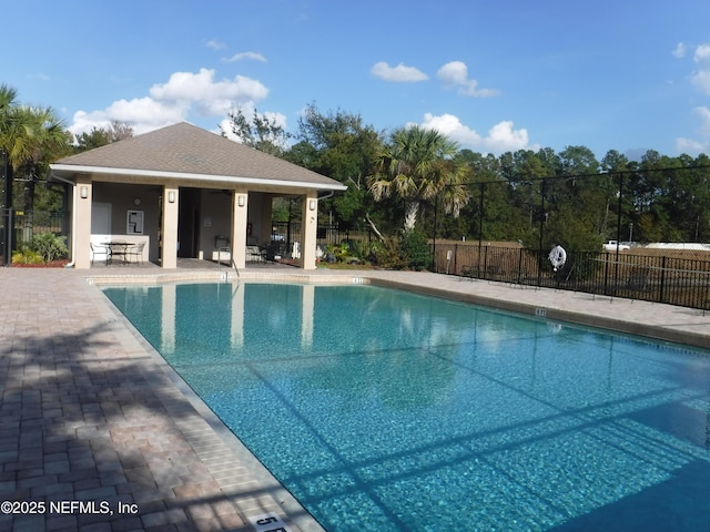 community pool with a patio area and fence