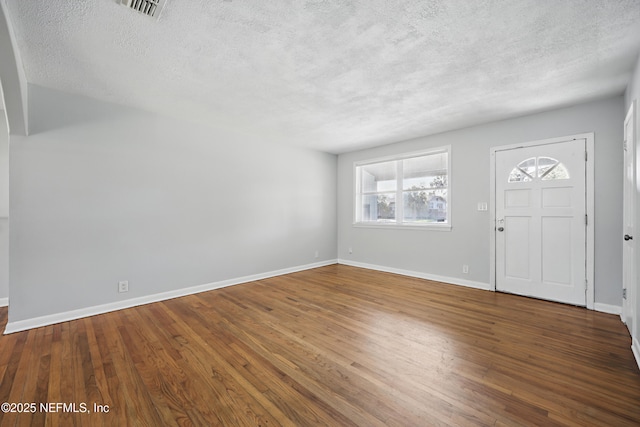 foyer with visible vents, a textured ceiling, baseboards, and wood finished floors