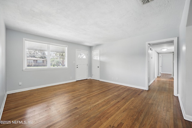 interior space featuring visible vents, baseboards, a textured ceiling, and hardwood / wood-style floors