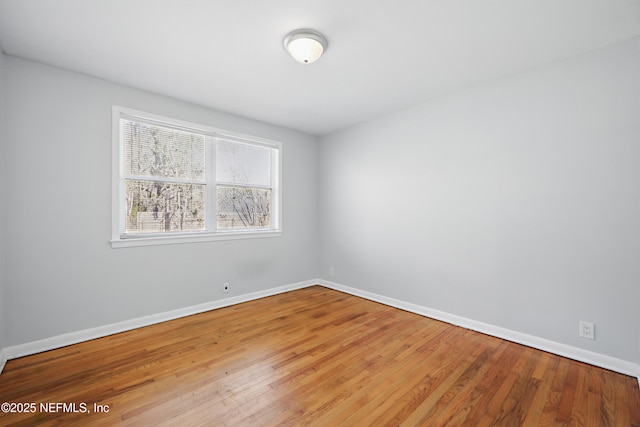 spare room featuring baseboards and wood finished floors