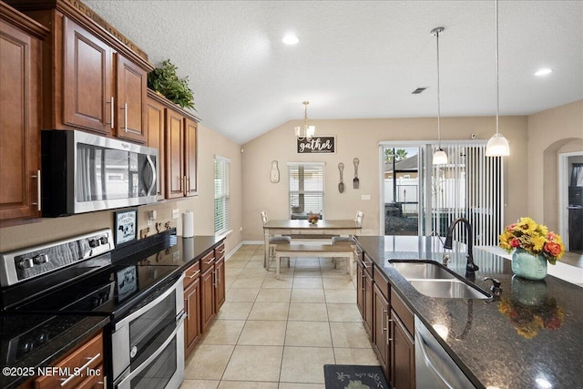 kitchen featuring pendant lighting, appliances with stainless steel finishes, light tile patterned flooring, a sink, and a textured ceiling