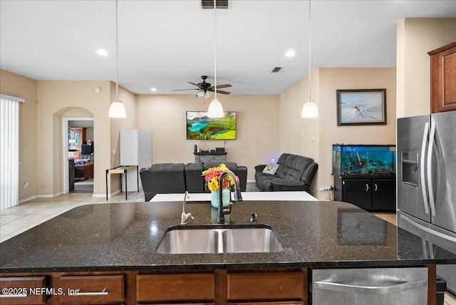 kitchen with an island with sink, appliances with stainless steel finishes, open floor plan, and a sink