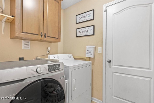 laundry area featuring baseboards, cabinet space, and washing machine and clothes dryer