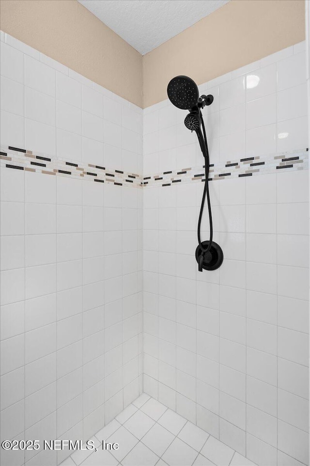 full bath with a textured ceiling and tiled shower