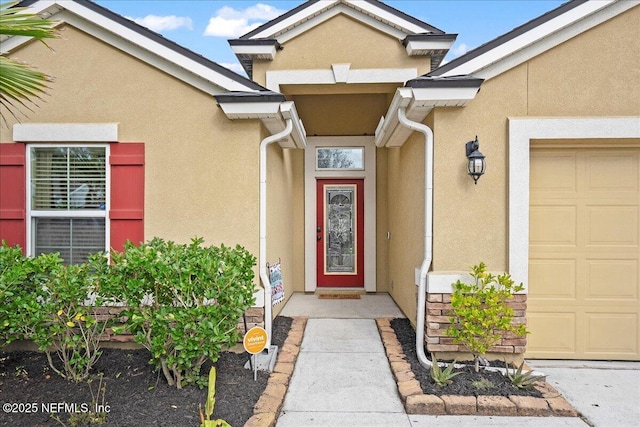 doorway to property featuring a garage and stucco siding