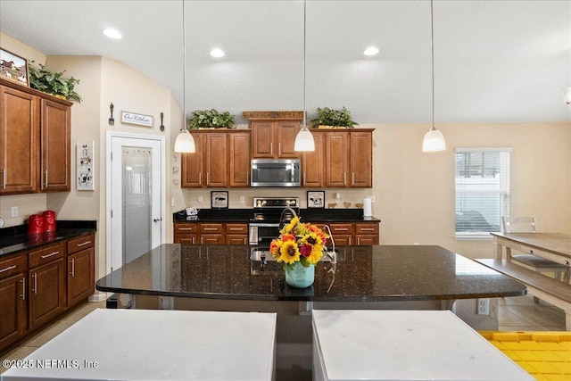 kitchen featuring stainless steel appliances, a breakfast bar, brown cabinetry, and pendant lighting