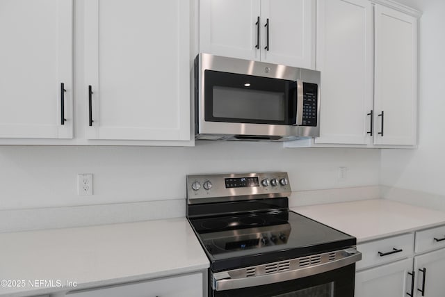 kitchen featuring stainless steel appliances, white cabinets, and light countertops