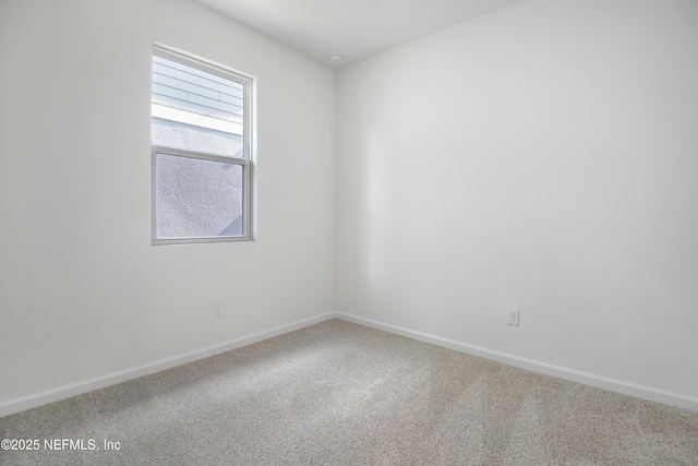 carpeted spare room featuring baseboards