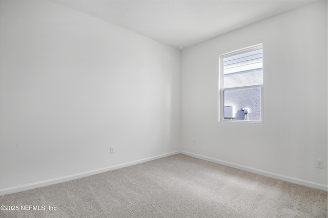 carpeted spare room featuring baseboards