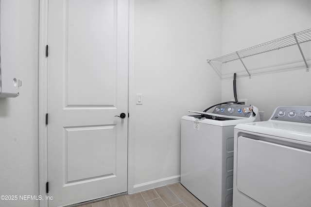 clothes washing area with laundry area, wood finish floors, independent washer and dryer, and baseboards