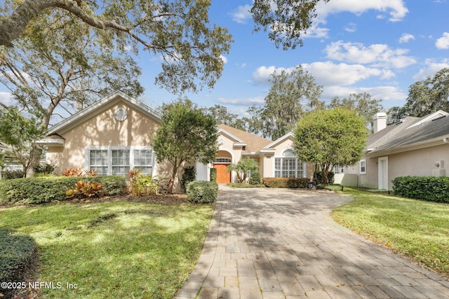 view of front of home with a front yard, decorative driveway, and stucco siding