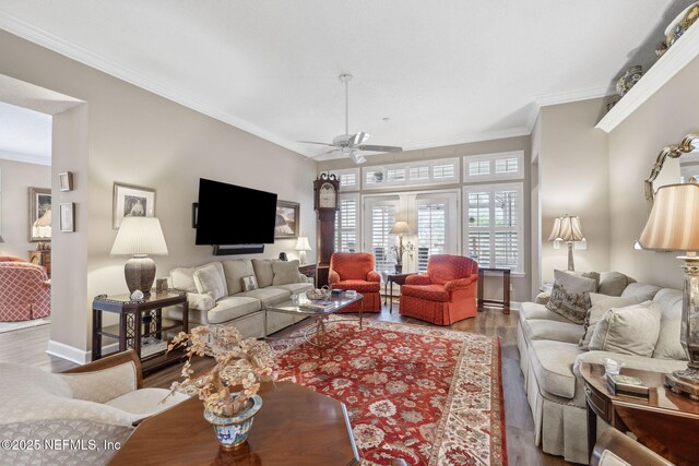 living room with a ceiling fan, crown molding, baseboards, and wood finished floors