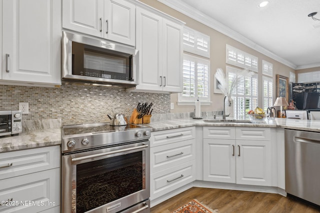 kitchen with a sink, white cabinetry, stainless steel appliances, and crown molding
