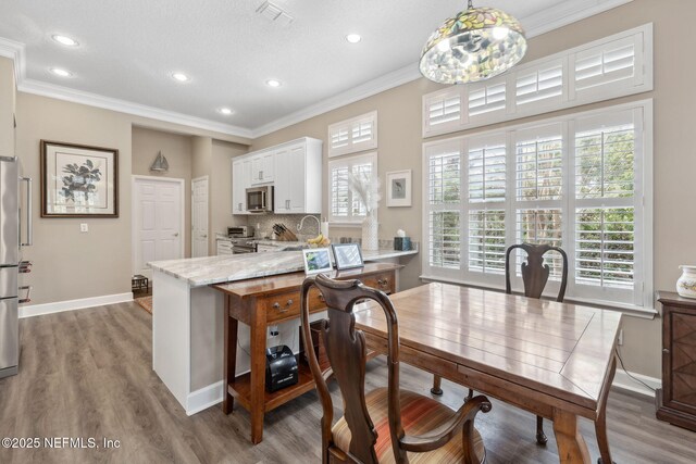 kitchen featuring crown molding, stainless steel appliances, decorative backsplash, white cabinets, and wood finished floors