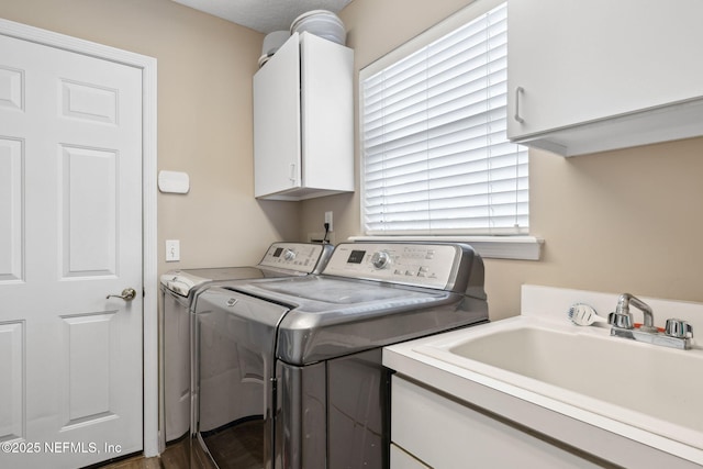 laundry area with cabinet space, separate washer and dryer, and a sink