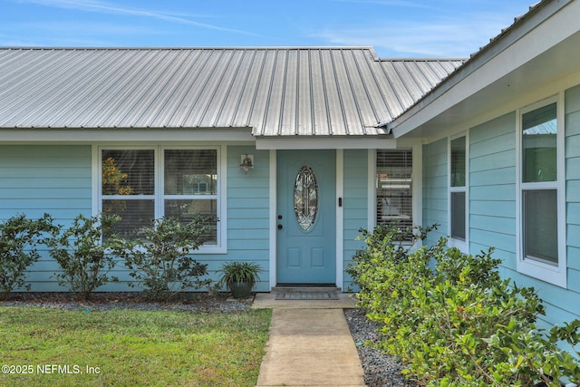 property entrance with metal roof and a lawn