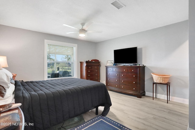 bedroom featuring a ceiling fan, light wood-type flooring, visible vents, and baseboards