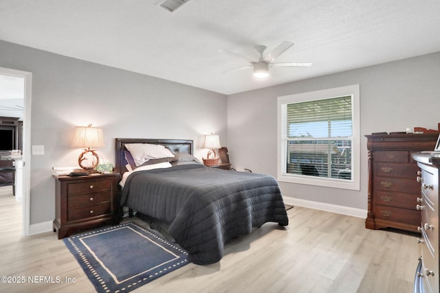 bedroom with visible vents, a ceiling fan, light wood-style flooring, and baseboards