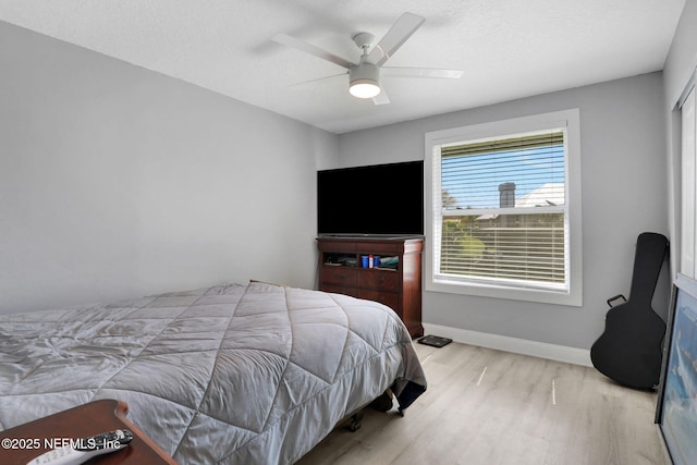 bedroom with a textured ceiling, wood finished floors, a ceiling fan, and baseboards