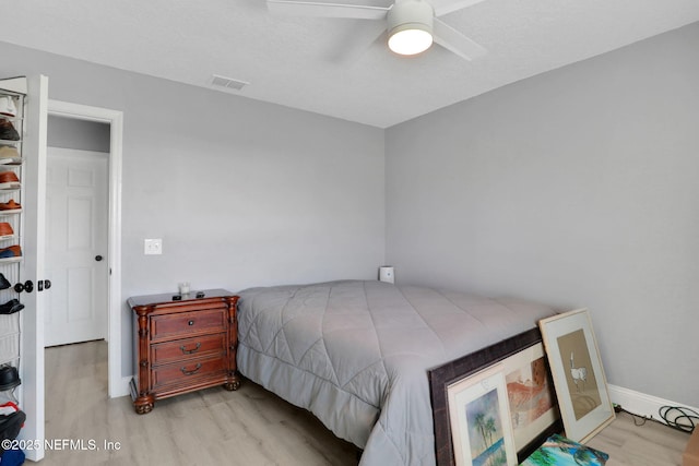 bedroom with a ceiling fan, baseboards, visible vents, and wood finished floors