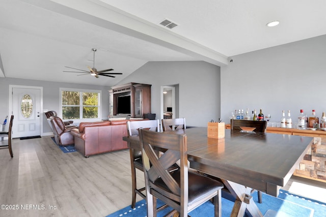 dining room with lofted ceiling, a ceiling fan, visible vents, light wood-style floors, and a bar