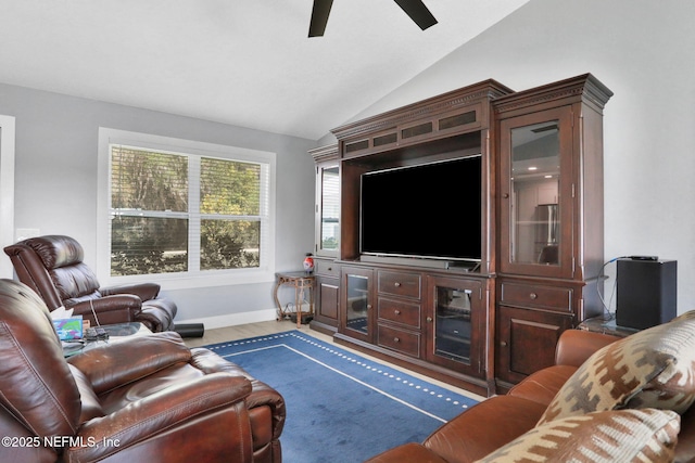 living room featuring lofted ceiling, ceiling fan, baseboards, and wood finished floors
