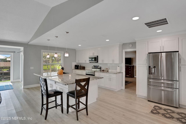 kitchen featuring visible vents, appliances with stainless steel finishes, light stone counters, a center island, and white cabinetry