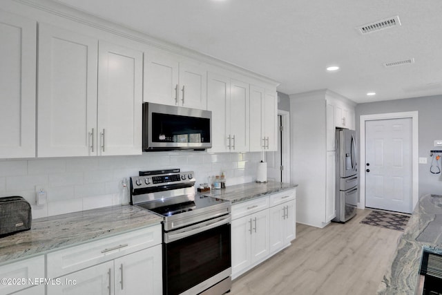 kitchen with visible vents, appliances with stainless steel finishes, white cabinets, and light wood-style flooring