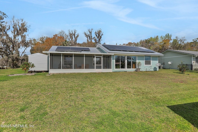 rear view of property with metal roof, a lawn, a sunroom, and roof mounted solar panels