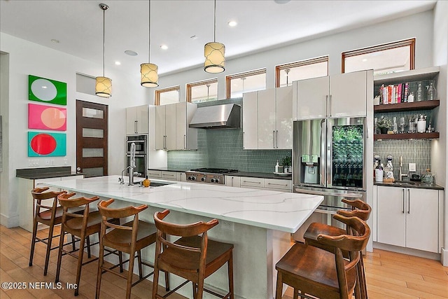 2446 Seminole Rd, Atlantic Beach, FL 32233 - kitchen with decorative light fixtures, tasteful backsplash, appliances with stainless steel finishes, light wood-style floors, and exhaust hood
