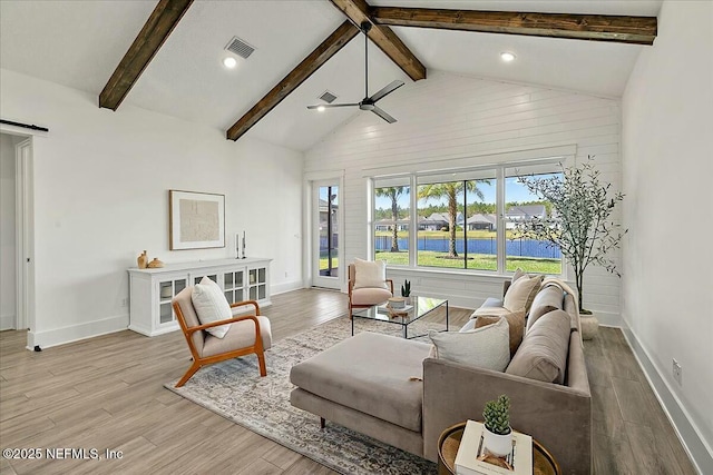 living room with visible vents, a barn door, beam ceiling, wood finished floors, and a ceiling fan