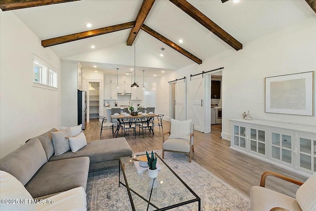 living room featuring light wood-style flooring, recessed lighting, a barn door, baseboards, and vaulted ceiling with beams